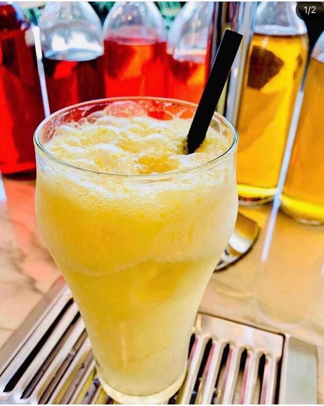 A tall glass of pale yellow slush at the marble fountain.