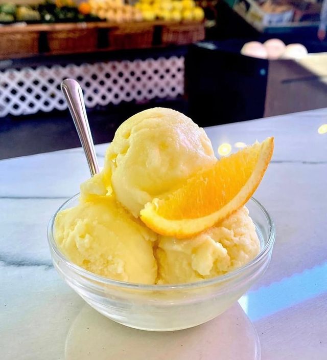 A glass dish of yellow scoops with slices of orange.