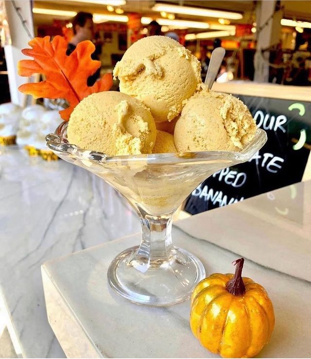 A coupe of scoops on the counter with autumn leaves and a pumpkin.